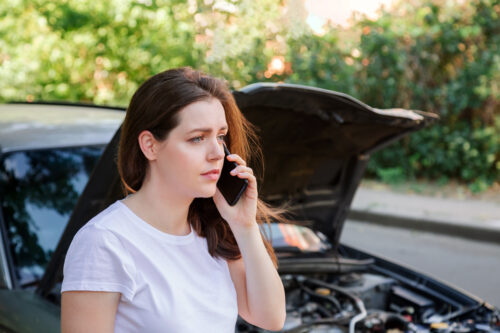 woman on phone in front of her car